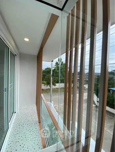 Modern balcony with glass railing and wooden accents offering a serene view.