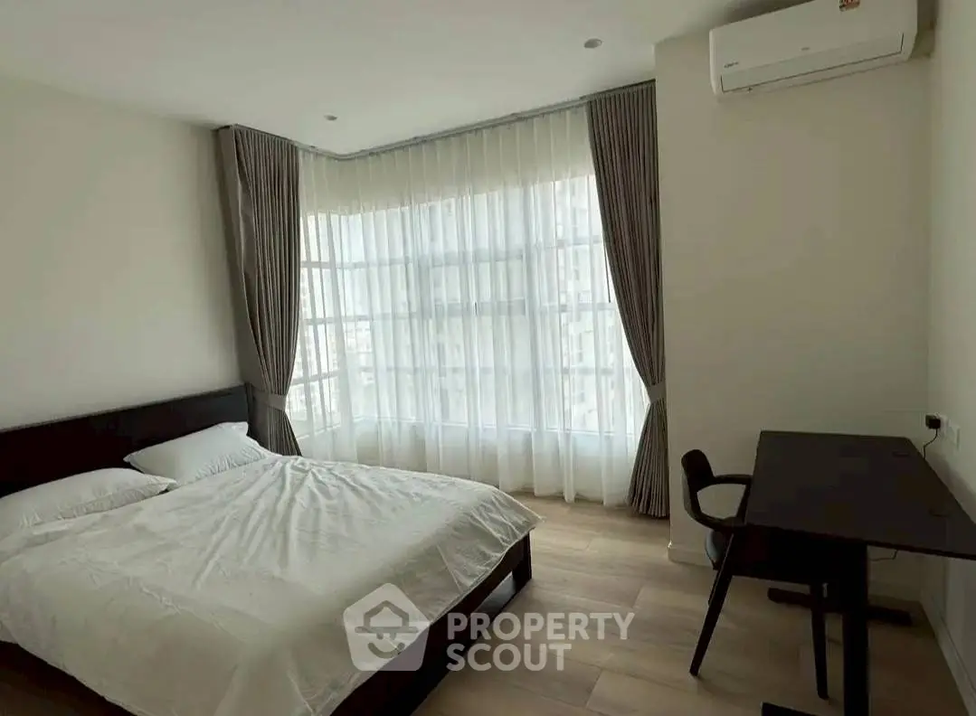 Spacious bedroom with large windows and modern furnishings