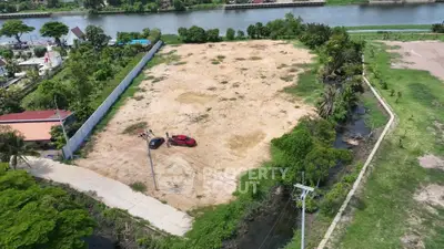 Expansive riverfront land plot with lush greenery, ideal for development opportunities.