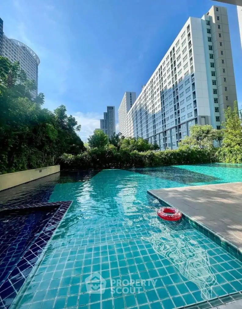 Luxurious residential pool with stunning high-rise building backdrop and lush greenery.