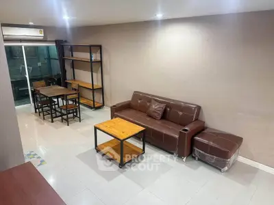 Spacious living room with modern brown leather sofa and dining area, perfect for relaxation and entertaining.
