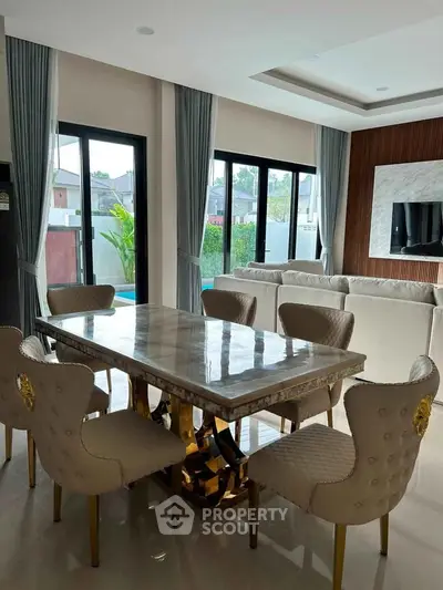 Luxurious dining area with elegant chairs and marble table, overlooking a serene pool view.