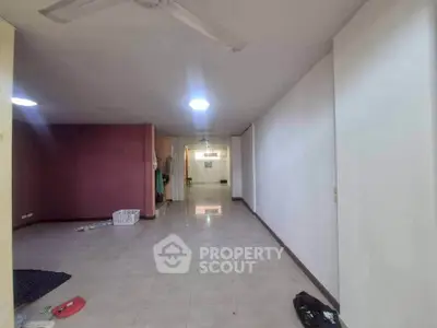 Spacious empty room with tiled flooring and ceiling fans, ideal for customization.