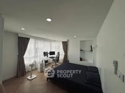 Modern bedroom with workspace and large windows, featuring sleek design and ample natural light.