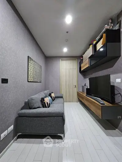 Modern living room with sleek grey sofa and wall-mounted TV unit