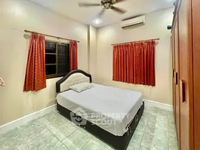 Cozy bedroom with air conditioning and ceiling fan, featuring red curtains and a comfortable bed.