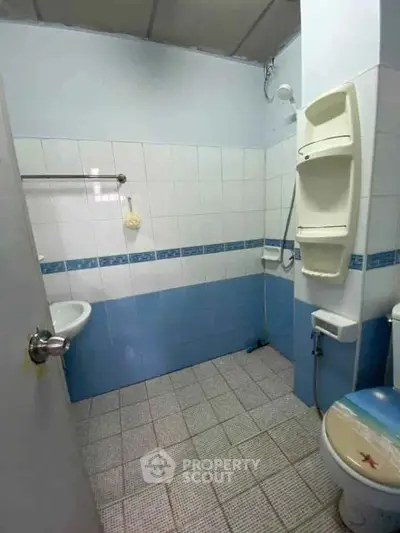 Spacious bathroom with blue and white tiles, featuring a shower and toilet.