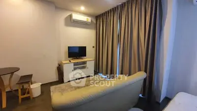 Cozy living room with modern decor and natural light, featuring a comfortable sofa and a flat-screen TV.