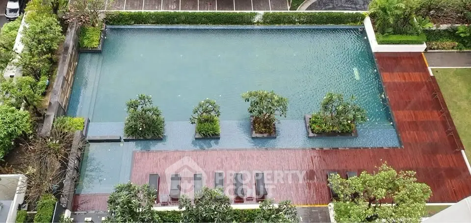 Luxurious rooftop pool with lush greenery and wooden deck in a modern residential complex.