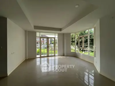 Spacious empty room with large windows and garden view, perfect for customization.