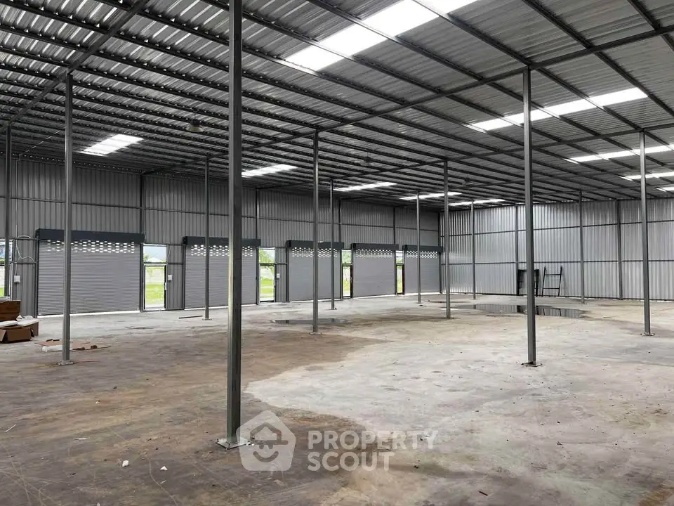 Spacious industrial warehouse interior with high ceilings and metal framework.