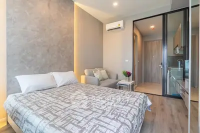 Modern bedroom with cozy seating area and sleek kitchenette, perfect for urban living.