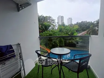 Charming balcony with pool view and lush greenery, perfect for relaxation and outdoor dining.
