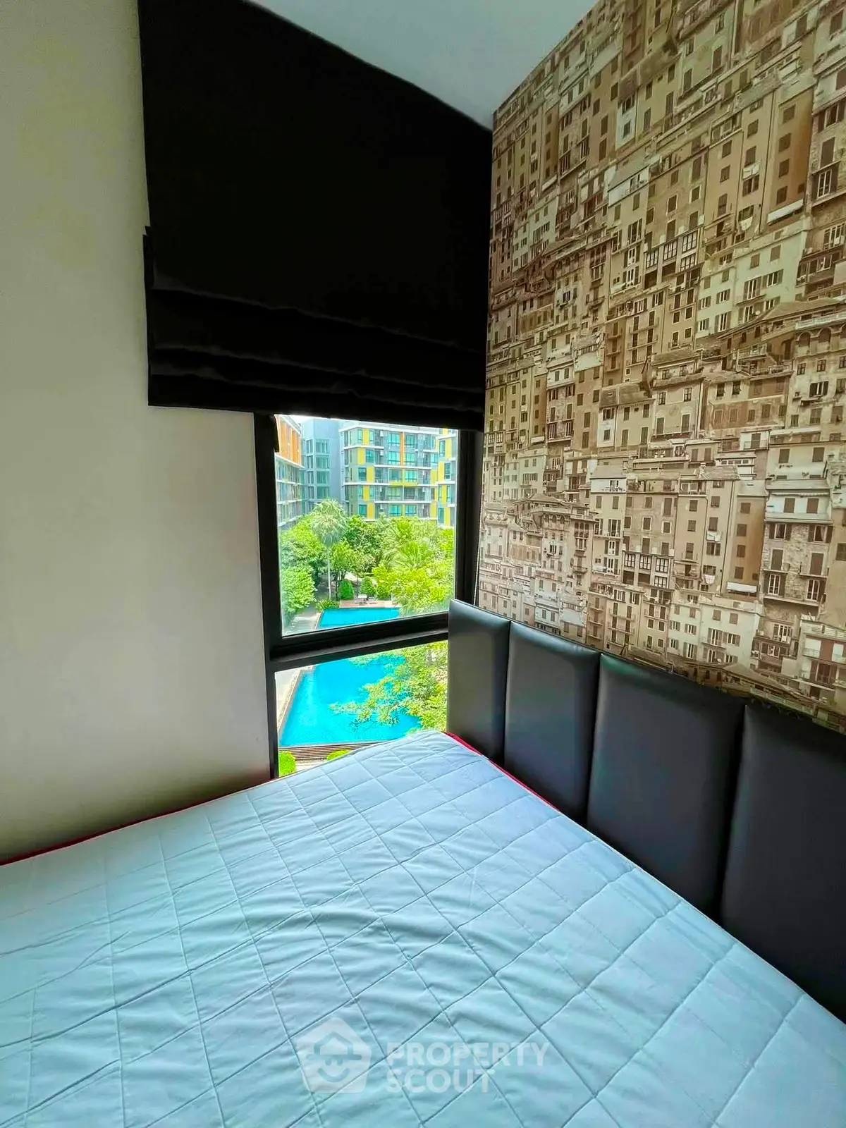 Cozy bedroom with cityscape wallpaper and pool view, perfect for urban living.