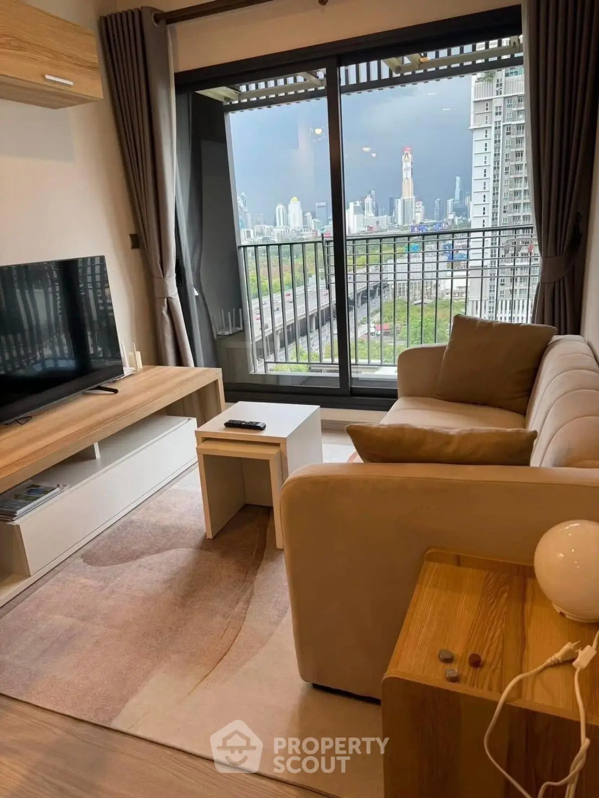 Modern living room with city view, cozy sofa, and sleek TV setup.