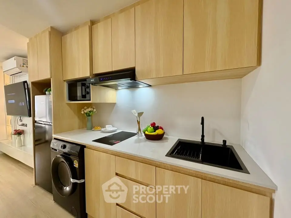 Modern kitchen with sleek wooden cabinets, induction cooktop, and integrated washing machine.