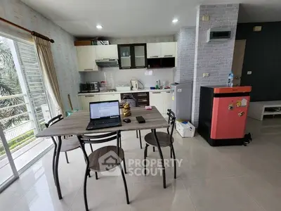 Modern kitchen with open layout and balcony view, featuring sleek appliances and dining area.