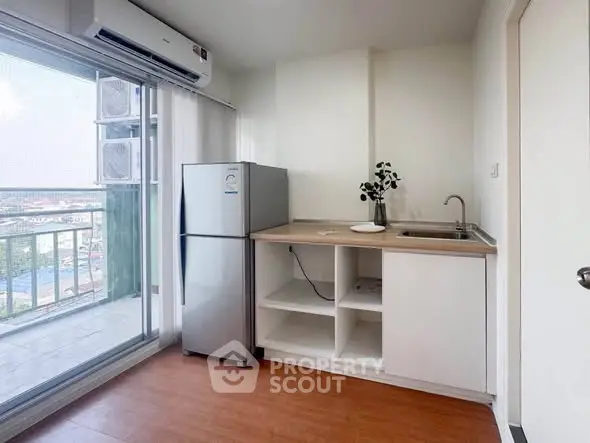 Modern compact kitchen with balcony view, featuring sleek appliances and minimalist design.