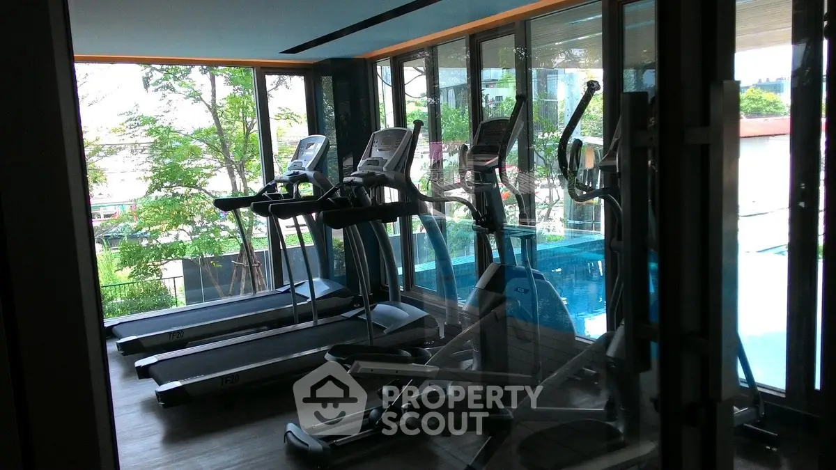 Modern gym with treadmills and pool view in luxury residential building.