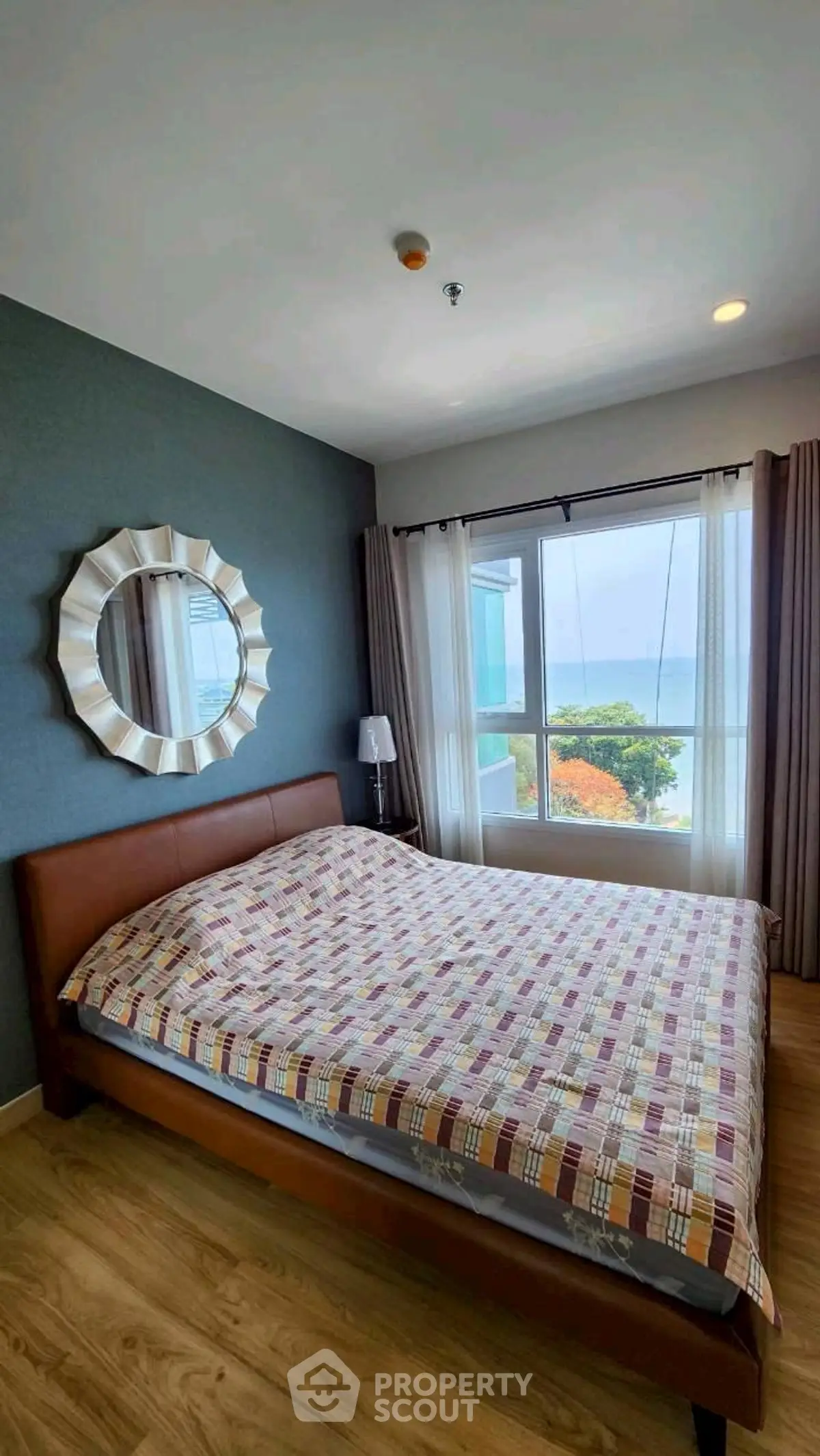 Cozy bedroom with ocean view, stylish decor, and ample natural light.