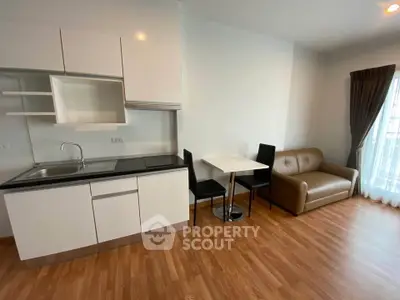 Modern apartment with sleek kitchen and cozy living area, featuring hardwood floors and natural light.