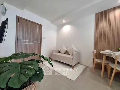 Modern living room with cozy sofa and dining area, featuring stylish decor and indoor plant.