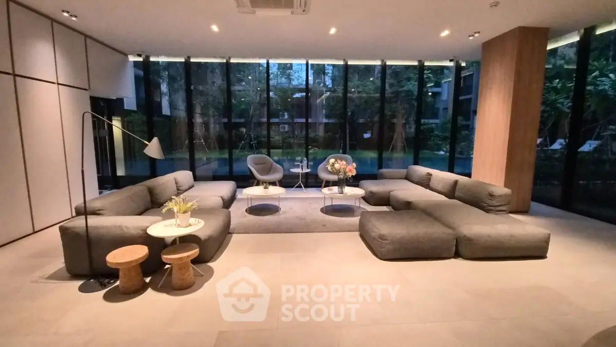 Luxurious modern living room with large windows and stylish furniture, offering a serene garden view.