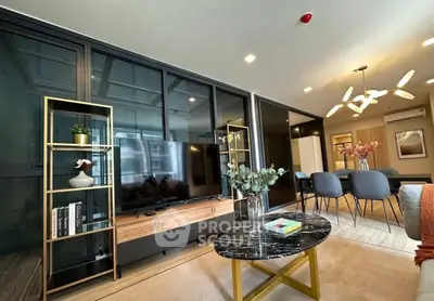 Modern living room with sleek decor and open dining area, featuring stylish furniture and elegant lighting.