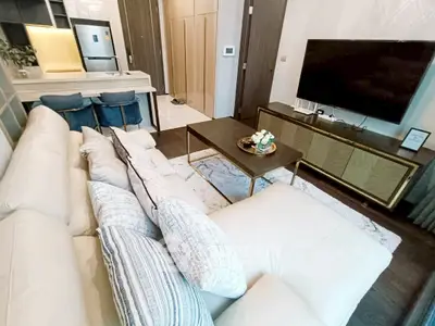 Modern living room with plush white sofa, sleek TV unit, and stylish kitchen area.