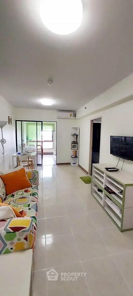 Modern living room with colorful sofa and wall-mounted TV in bright apartment