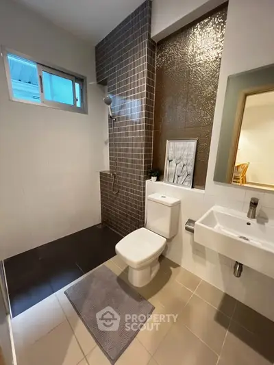 Modern bathroom with sleek design, featuring a shower area, toilet, and stylish sink.