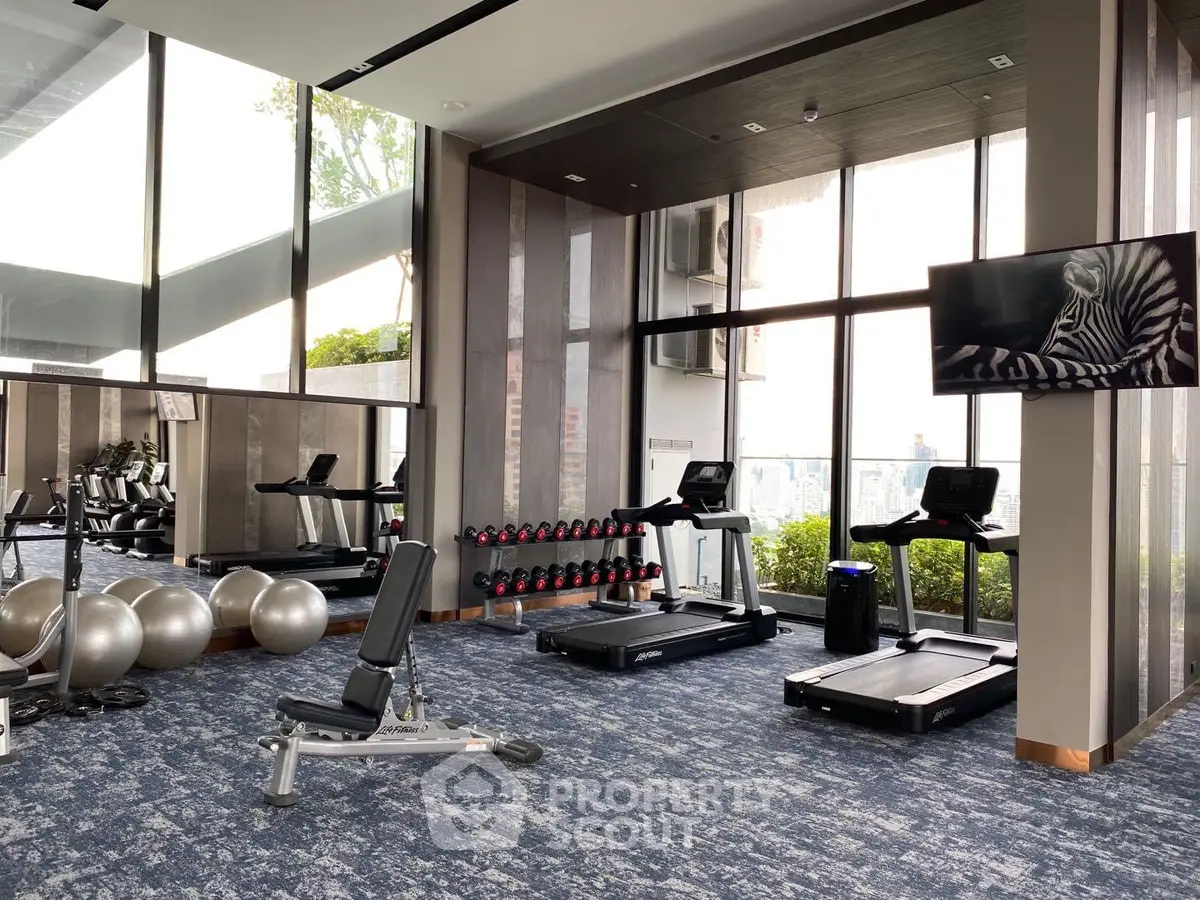 Modern gym with treadmills and exercise equipment in a high-rise building with city views.