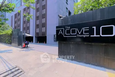 Modern building entrance with sleek design and lush greenery at The Alcove Thonglor 10.