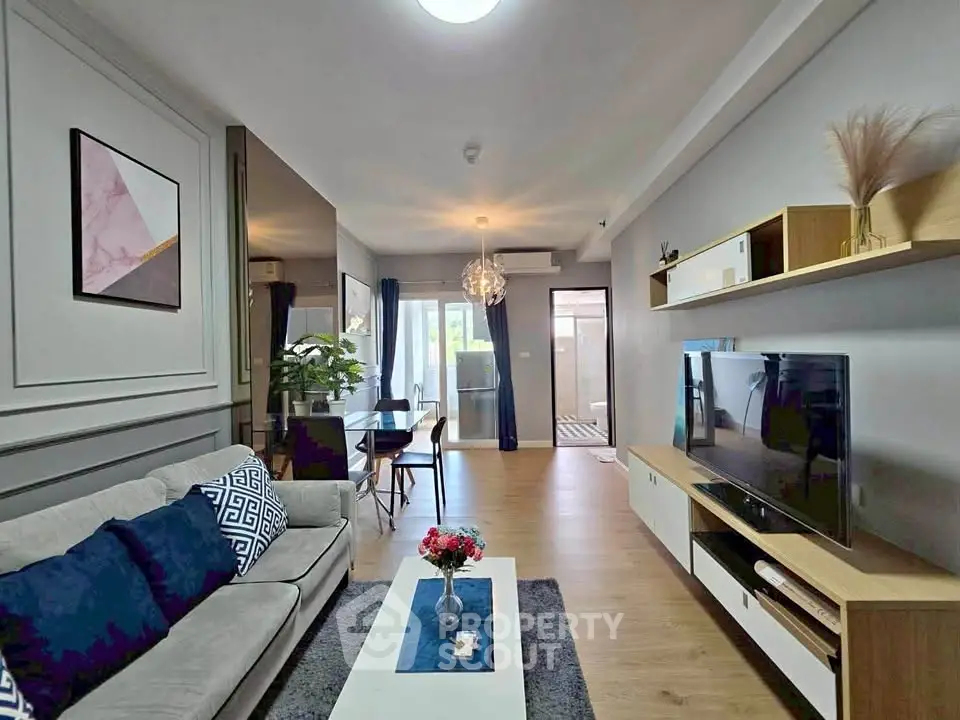 Modern living room with stylish decor and open layout, featuring a cozy sofa and large TV unit.