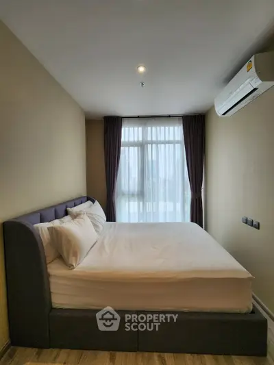Cozy bedroom with modern decor and large window offering natural light.