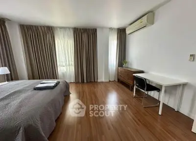 Spacious bedroom with wooden flooring, air conditioning, and natural light.
