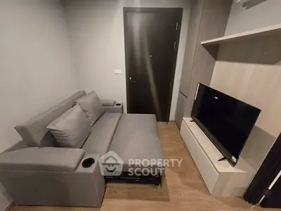 Modern living room with sleek gray sofa and flat-screen TV, perfect for cozy relaxation.