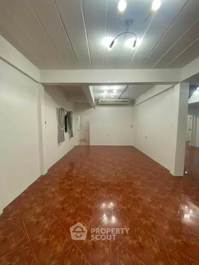 Spacious empty room with glossy tiled floor and modern lighting, perfect for customization.