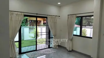 Bright living room with large windows and garden view, perfect for relaxation.