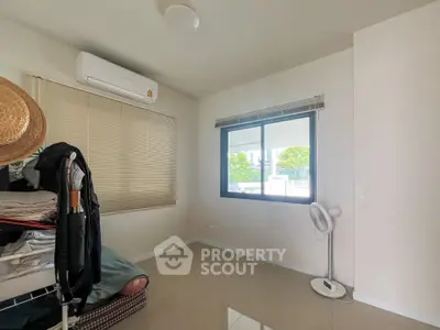 Spacious bedroom with air conditioning and large window offering natural light and garden view.