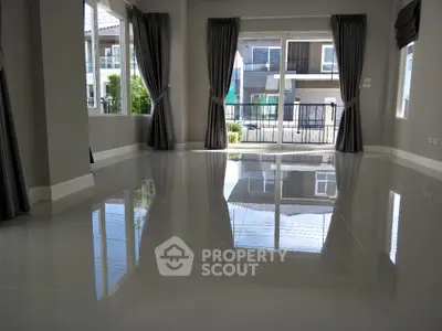 Spacious modern living room with large windows and glossy tile flooring in a contemporary home.