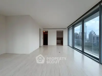 Spacious modern living room with floor-to-ceiling windows and city skyline view.