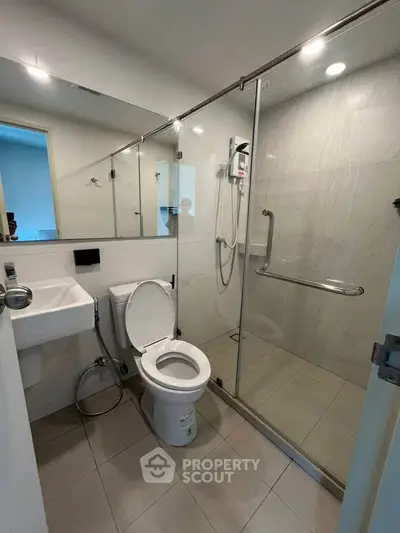Modern bathroom with glass shower enclosure and sleek fixtures in a contemporary apartment.
