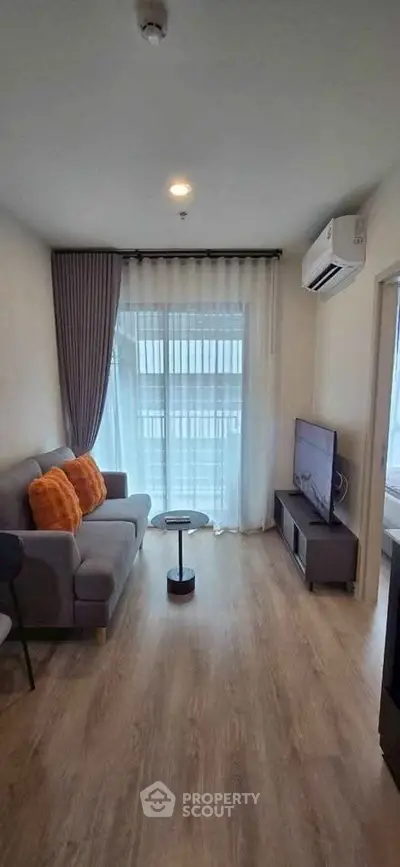Modern living room with cozy sofa, TV, and large window with balcony view.