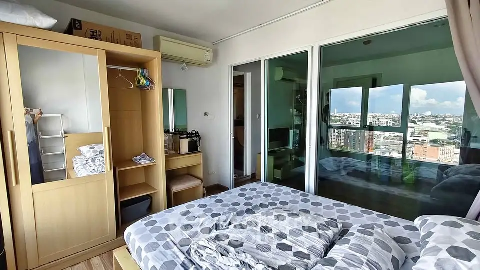 Modern bedroom with city view, featuring a cozy bed, wardrobe, and air conditioning.