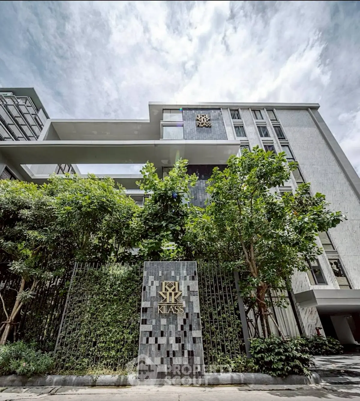 Modern architectural building with lush greenery and stylish facade in urban setting.