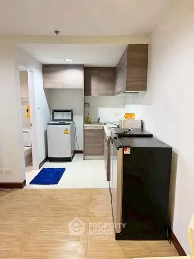 Modern kitchen with washing machine and sleek cabinetry in cozy apartment