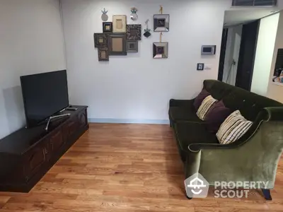 Charming living room with elegant green sofa and modern TV setup on wooden flooring.