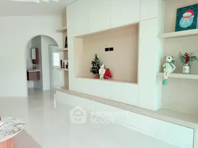 Modern living room with built-in shelving and festive decorations, showcasing sleek design and spacious layout.