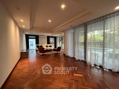 Spacious living room with elegant wooden flooring and large windows offering natural light.